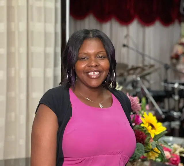 Woman posing with flowers and curtains
